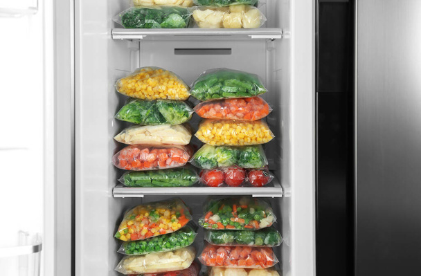 Buzdolabında farklı donmuş sebzeler olan plastik poşetler. - Fotoğraf, Görsel