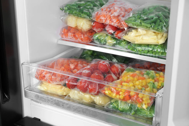 Plastic bags with different frozen vegetables in refrigerator - 写真・画像