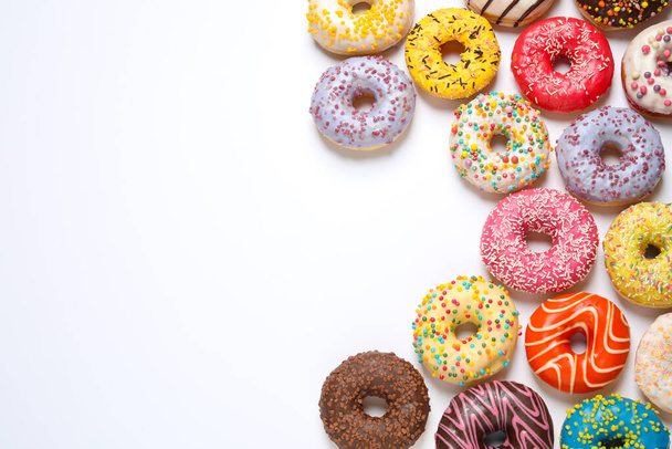 Delicious glazed donuts on white background, flat lay. Space for text - Zdjęcie, obraz