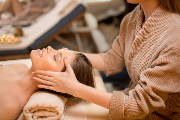 young woman getting head massage in spa salon - Foto, Bild
