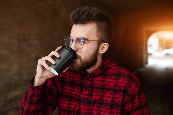 Bonito jovem barbudo bebendo café em taça takeaway ao ar livre
 - Foto, Imagem