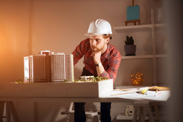 young professional architect leaning on his arm, thinking about the layout - Foto, Bild