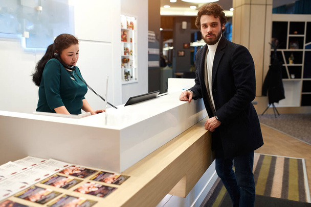 bearded handsome man looking at the camer while leaning on the receptions desk - 写真・画像