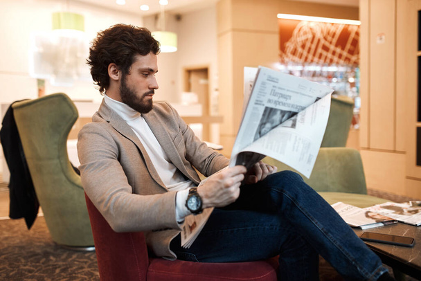guy sitting on the sofa, holding newspaper in hands - Fotografie, Obrázek