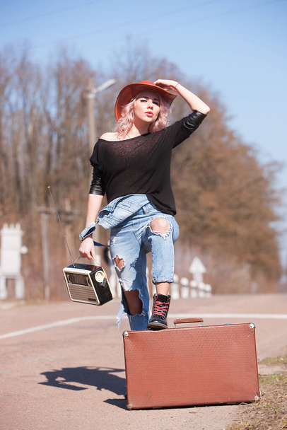 Mooie reizende vrouw met retro koffer op de weg - Foto, afbeelding