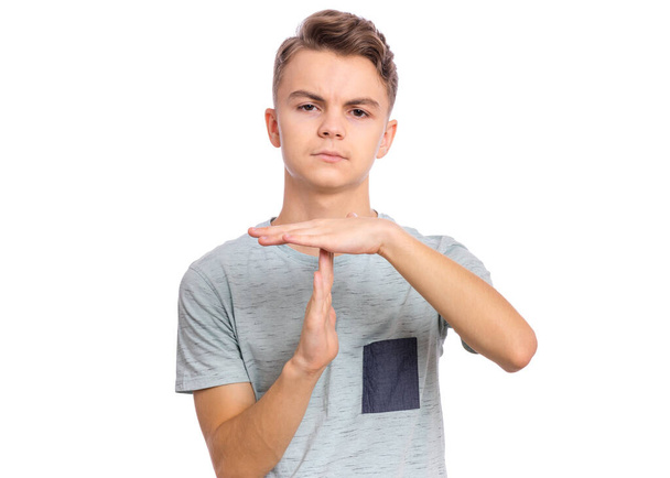 Emotional portrait of Teen Boy making timeout gesture, isolated on white background. Serious child tired and bored looking at camera and showing pause or time out sign. Student asking for time-out. - Photo, Image