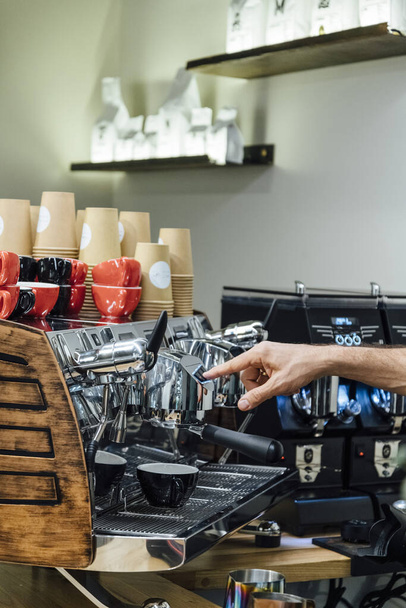 Közelkép barista tartja szűrő tartó miközben kávéfőző gép főzés friss eszpresszó üvegbe - Fotó, kép