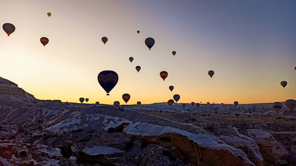 Colorful hot air balloons flying over the valley with fairy chimneys in winter season. Lots of Hot air balloons at the sunrise sky landscape in Cappadocia, Turkey - Foto, Bild