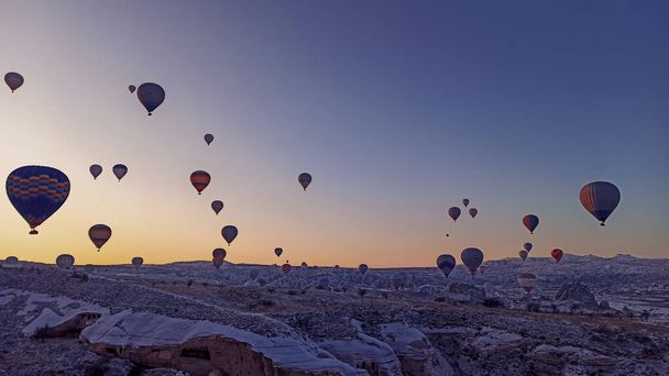 Colorful hot air balloons flying over the valley with fairy chimneys in winter season. Lots of Hot air balloons at the sunrise sky landscape in Cappadocia, Turkey - 写真・画像