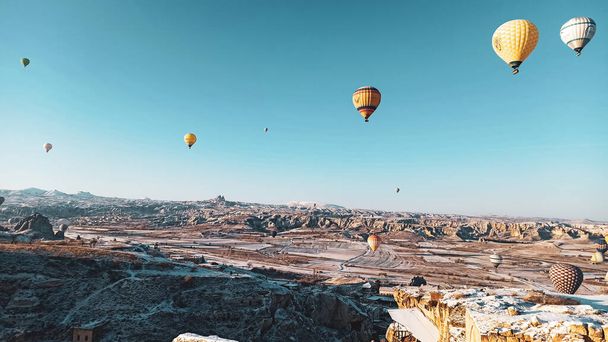 Colorful hot air balloons flying over the valley with fairy chimneys in winter season. Lots of Hot air balloons at the sunrise sky landscape in Cappadocia, Turkey - Zdjęcie, obraz