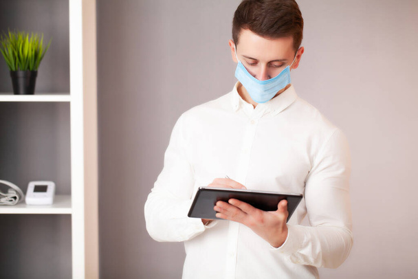 Чоловік, який працює в офісі, носить маску для захисту від коронавірусу
 - Фото, зображення