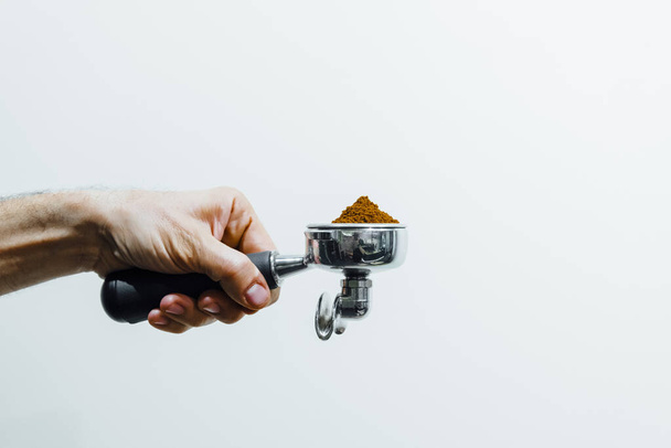 Деталь руки людини, що тримає портативний фільтр, наповнений кавовим майданчиком під час приготування еспресо
 - Фото, зображення