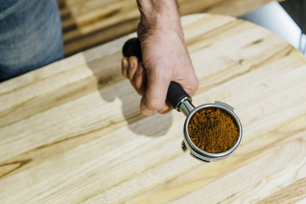 Détail de l'homme portafilter main tenant récipient rempli de café moulu lors de la préparation de l'expresso
 - Photo, image