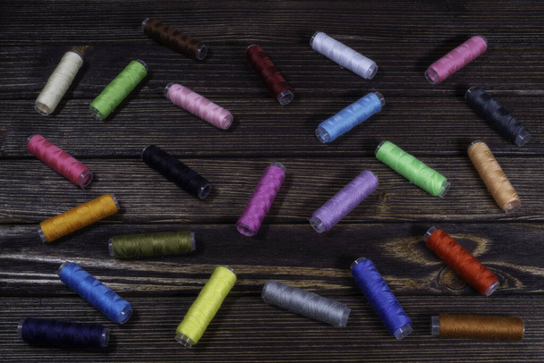 Grupo de carretéis de cores diferentes empoleirados em um tampo de mesa de madeira
 - Foto, Imagem