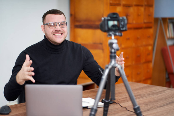 hombre filmando video blog en cámara con trípode para seguidores en línea. En las redes sociales, Influencer, nuevas tecnologías y concepto de internet
 - Foto, imagen