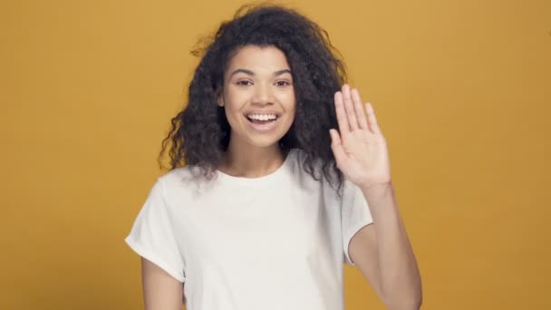 Portrait of afro american woman showing hello sign by hand. Yellow background. - Záběry, video