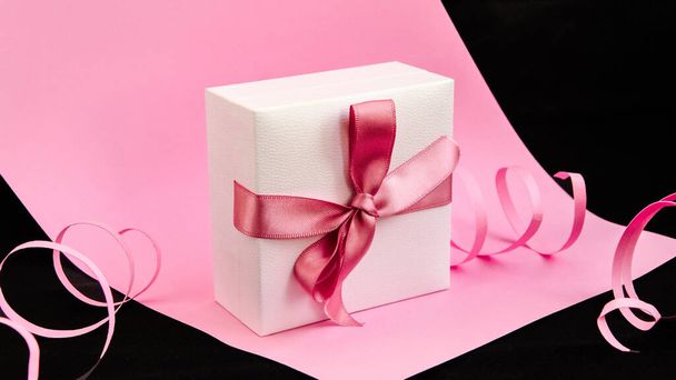 Caja de regalo con cinta rosa en el fondo rosa y negro, Vacaciones, Regalos, Espacio para copiar, Tarjeta de felicitación
 - Foto, imagen