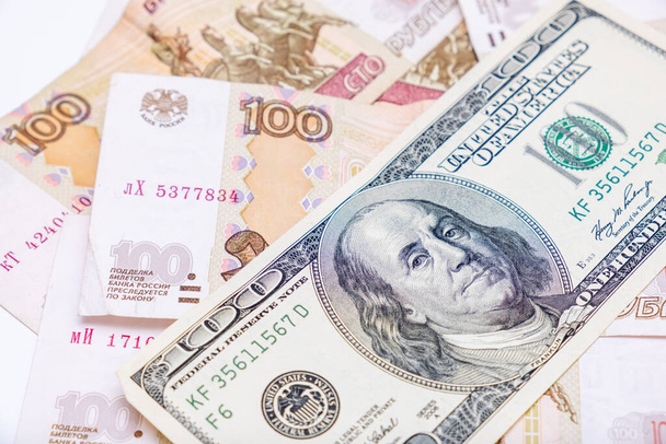 Us dollars banknotes lying over russian rubles background, financial crisis and choosing currency for savings, ruble devaluation concept. - 写真・画像