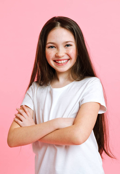 Portrait of adorable smiling little girl child in the white t-shirt isolated on a pink background - Foto, Imagem