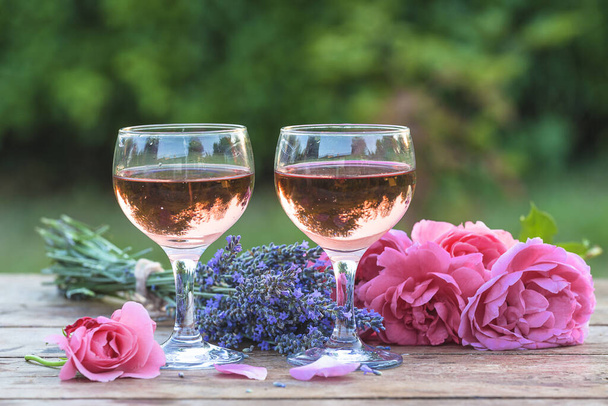Dois copos de vinho rosa, um monte de rosas rosa e um buquê de lavanda
 - Foto, Imagem