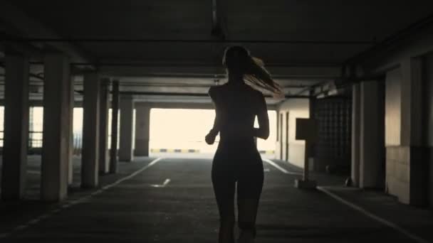 Silhouette of pretty sports woman running away outdoors - Кадри, відео