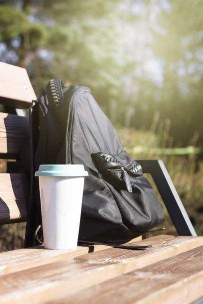 Trendy zero waste concept with reusable cup and black backpack. Natural morning background. Environmentally friendly, eco living. Toned image. - Photo, image