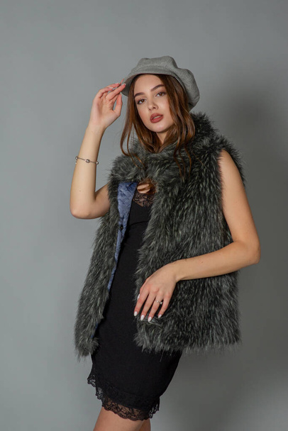 magnificent portrait of a beautiful young woman. Perfect face beautiful girl portrait. brunette girl. Girl in a gray hat. little black dress. Girl in a vest with faux fur. - Valokuva, kuva