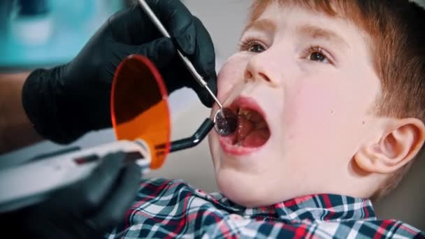 Ein kleiner Junge beim Zähneputzen - die Fotopolymerlampe in den Mund stecken und einschalten - Filmmaterial, Video