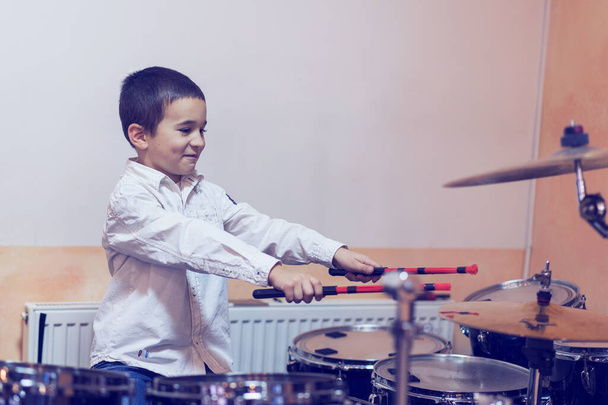 Junge trommeln. Junge im weißen Hemd spielt Schlagzeug. Ein Junge im weißen Hemd trommelt. gemildert. - Foto, Bild