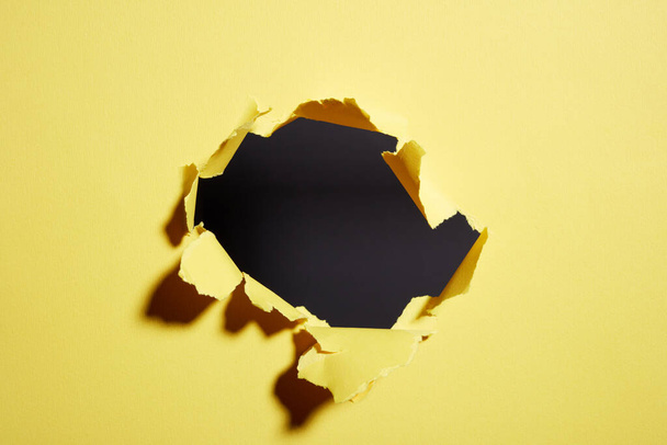 hole torn in the paper yellow background - Фото, зображення