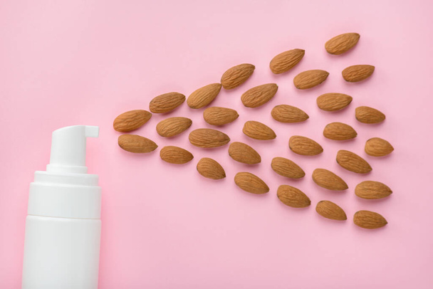 Top above overhead cropped close up view photo of bottle spreading almond nuts to the side isolated over pastel color background copy empty blank space - Photo, Image