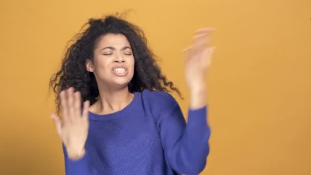Portrait of young afro american woman having fun, singing and dancing. Yellow background. - Filmati, video