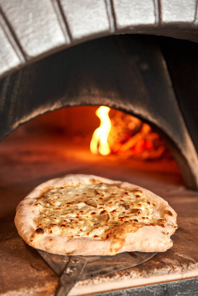 Baked tasty pizza with Gorgonzola and pear, in Traditional wood oven in Naples restaurant, Italy. Original neapolitan pizza. Red hot coal. - Photo, Image
