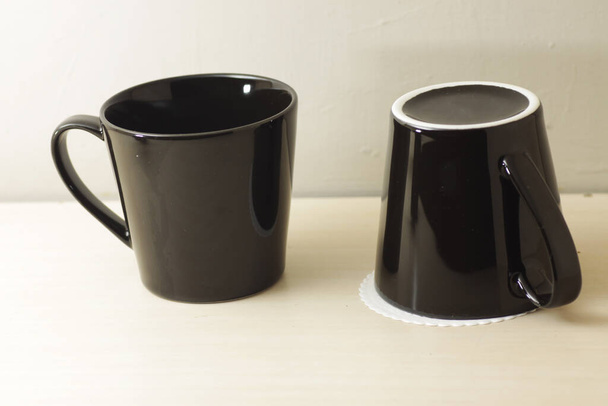 чорна порцелянова чашка на яскравому дерев'яному столі
 - Фото, зображення