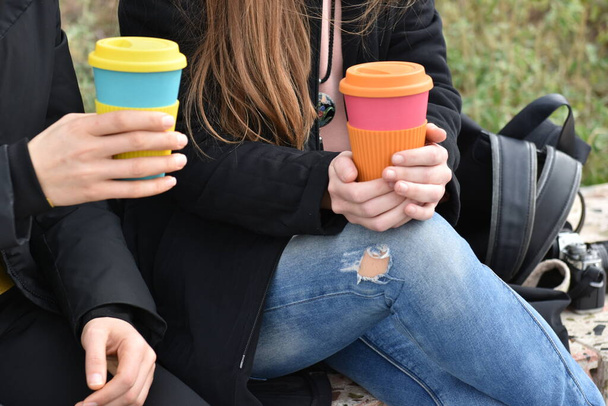 two girls sitting outdoors holding coffee cup .Sustainable lifestyle  - Fotografie, Obrázek
