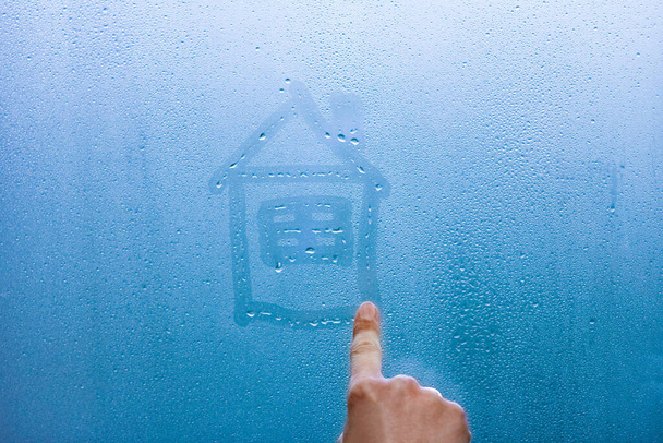 main dessine une maison sur une fenêtre en verre avec des gouttes de fond
 - Photo, image