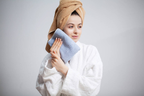 Woman wipes the face towel after taking a shower - Foto, afbeelding