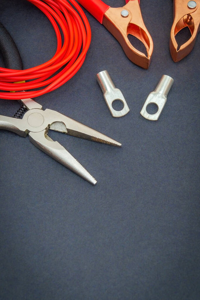 Duży zestaw części zamiennych i narzędzi, czerwone przewody elektryczne przygotowane przed naprawą lub ustawieniem na czarnym stole warsztatowym - Zdjęcie, obraz
