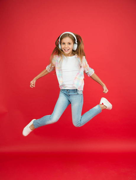 So much fun. Girl listening music modern gadget. Kid happy with wireless headset dancing jumping. Stereo headphones. Kid using modern technology. Modern child. Perfect sound. Never ending joy - 写真・画像
