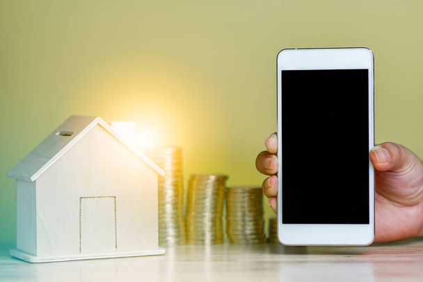 Αποθήκευση piggy τράπεζα ξύλινο σπίτι σε απομονωμένη μαύρη οθόνη smartphone, κλειδί και κέρματα στοίβα για έξυπνο σπίτι σύστημα τηλεχειρισμού internet ψηφιακή τραπεζική ασφάλεια δανείου για ενυπόθηκη χρηματοδότηση από το κινητό app - Φωτογραφία, εικόνα