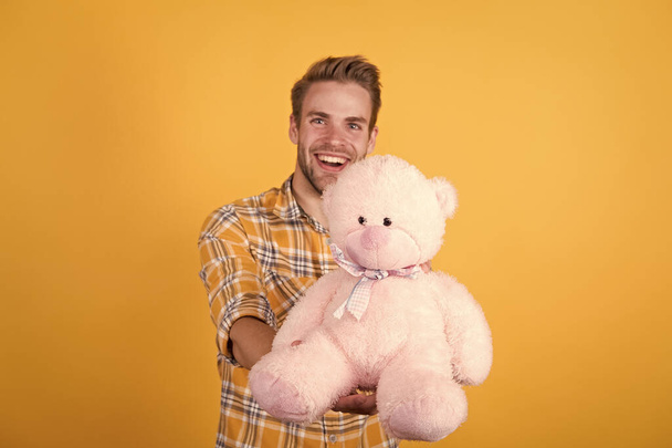 Buying gift. cheerful guy present yellow background. happy birthday to you. happy valentines day. inspired to play. teddy bear plush toy pleasant surprise. his favorite toy. macho man teddy bear gift - Foto, immagini