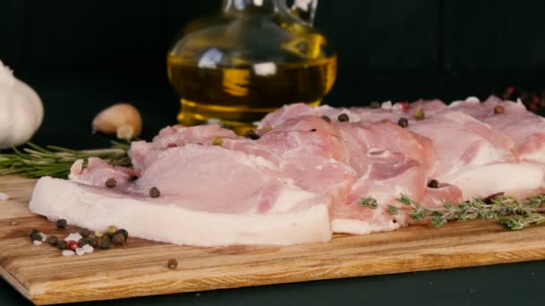 Fatias frescas de carne de bacon de porco em uma placa de cozinha de madeira em um estilo rústico. Alho, ramo de alecrim, sal grosso, pimenta, azeite. Cozinha caseira
. - Filmagem, Vídeo