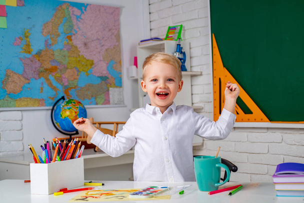 Happy child boy in classroom near blackboard desk. Funny school kids at lesson. Portrait of Pupil of primary school study indoors. - Foto, imagen