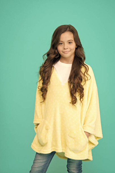 Comfy style. Kid wearing soft poncho. Wellbeing concept. Little girl with long hair. Happy childhood. Feeling comfy. Adorable child on turquoise background. Comfy outfit for weekend rest at home - Fotografie, Obrázek
