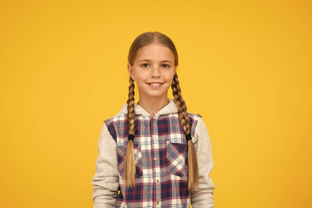 cute smile. hipster girl yellow background. happy school girl casual style. kid fashion. child cute blond hair. childhood happiness. happy childrens day. small girl checkered jacket. autumn time - Foto, afbeelding