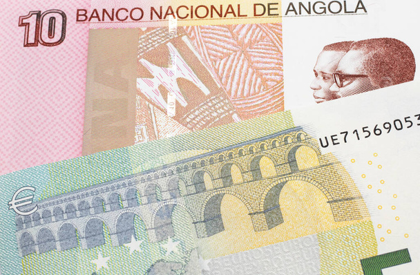 A colorful ten kwanza bill from Angola with a blue and green, European 5 euro bank note close up in macro - Photo, Image