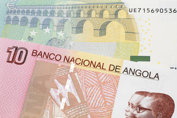A colorful ten kwanza bill from Angola with a blue and green, European 5 euro bank note close up in macro - Fotoğraf, Görsel