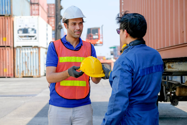Tecnico o lavoratore dare casco di sicurezza al suo collega nella zona di spedizione container carico
. - Foto, immagini