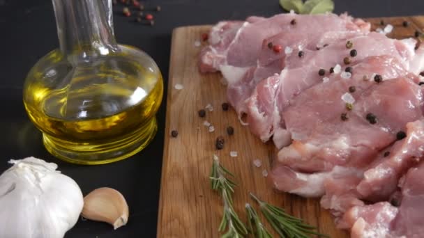 Friss, nagy rózsaszín szalonnahús húsdarabok az otthoni főzés vágódeszkáján, rusztikus stílusban, fekete és vörös borssal és durva sóval díszítve - Felvétel, videó