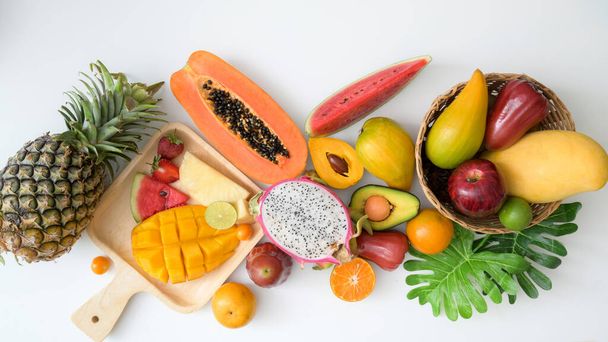 Над головой снимок ассортимента экзотических фруктов, летних фруктов, тропических фруктов и листьев на белом фоне
 - Фото, изображение